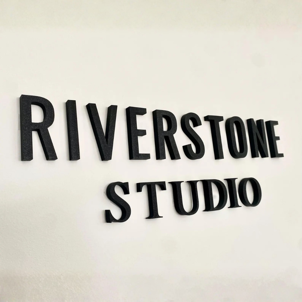 3D printed black signage letters mounted on a wall
